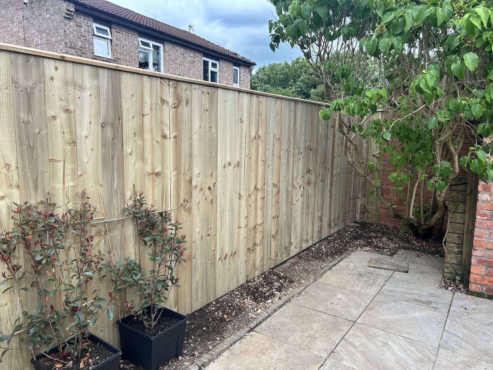 New closeboard timber fence along a patio with potted shrubs, fitted by A.Garner Fencing & Landscapes